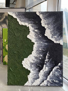 Close-up of a hand-painted 3D textured abstract painting featuring heavy white sculpted foam over moss green and black backgrounds in a gold frame.