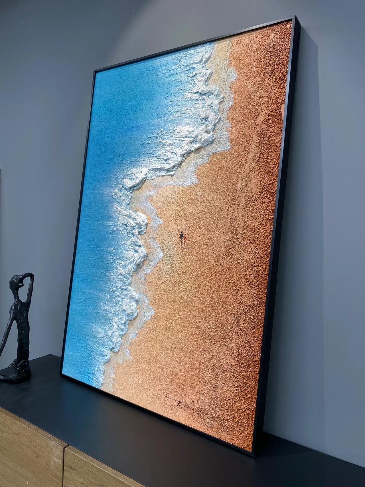 Hand-painted 3D textured aerial view of beach waves with heavy white sculpted foam and granular golden sand texture in a gold frame.