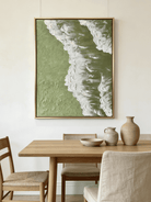 High-relief 3D textured painting showing white sculpted seafoam splashing over a deep forest green background in a gold frame.