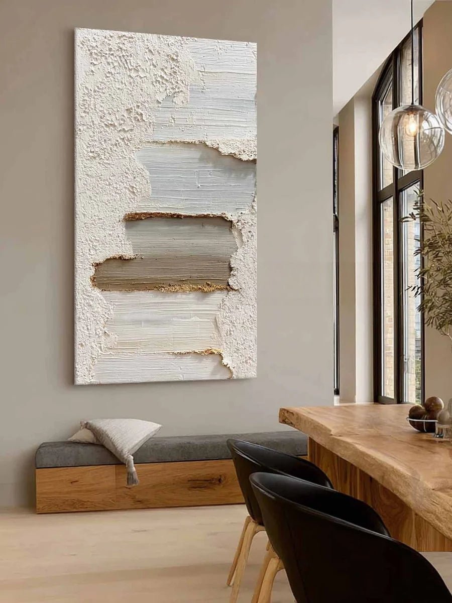 A tall vertical 3D textured abstract painting by Leo Liang featuring heavy plaster-like layers of white, taupe, and gray in a modern living room with a fireplace.