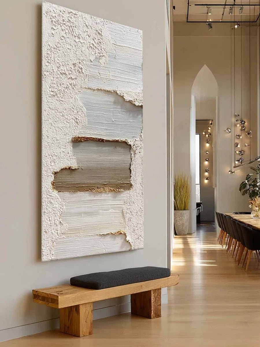A tall vertical 3D textured abstract painting by Leo Liang featuring heavy plaster-like layers of white, taupe, and gray in a modern living room with a fireplace.