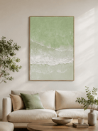Sage green coastal painting displayed above a neutral sofa in an organic modern living room