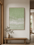 Vertical sage green shoreline painting displayed above a wood console in a minimalist modern entryway