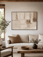 Neutral textured abstract painting displayed above a beige sofa in an organic modern living room