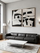 A pair of modern minimalist oil paintings with bold geometric shapes hanging as a diptych above a contemporary living room sofa.