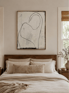 Neutral line art female figure displayed above a bed in a warm minimalist bedroom