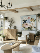 Large square 3D textured floral painting showing heavy impasto pink and white flowers on a light blue background in a modern living room.