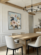 Large square 3D textured floral painting showing heavy impasto pink and white flowers on a light blue background in a modern living room.