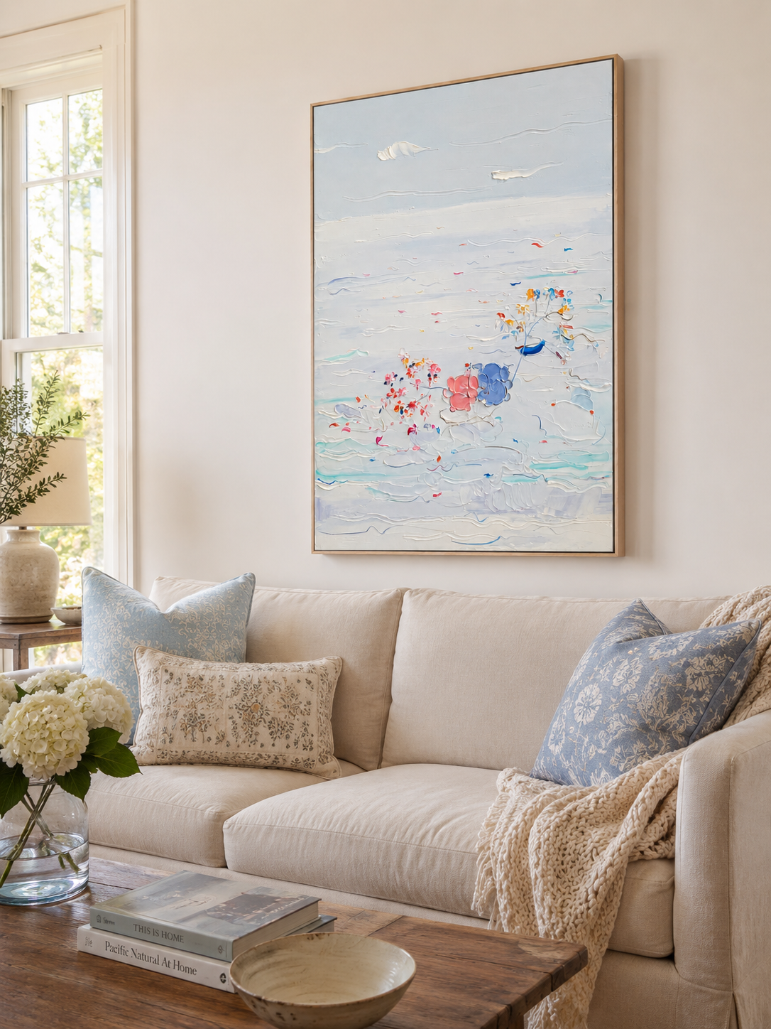 Textured coastal canvas displayed above a cream living room sofa