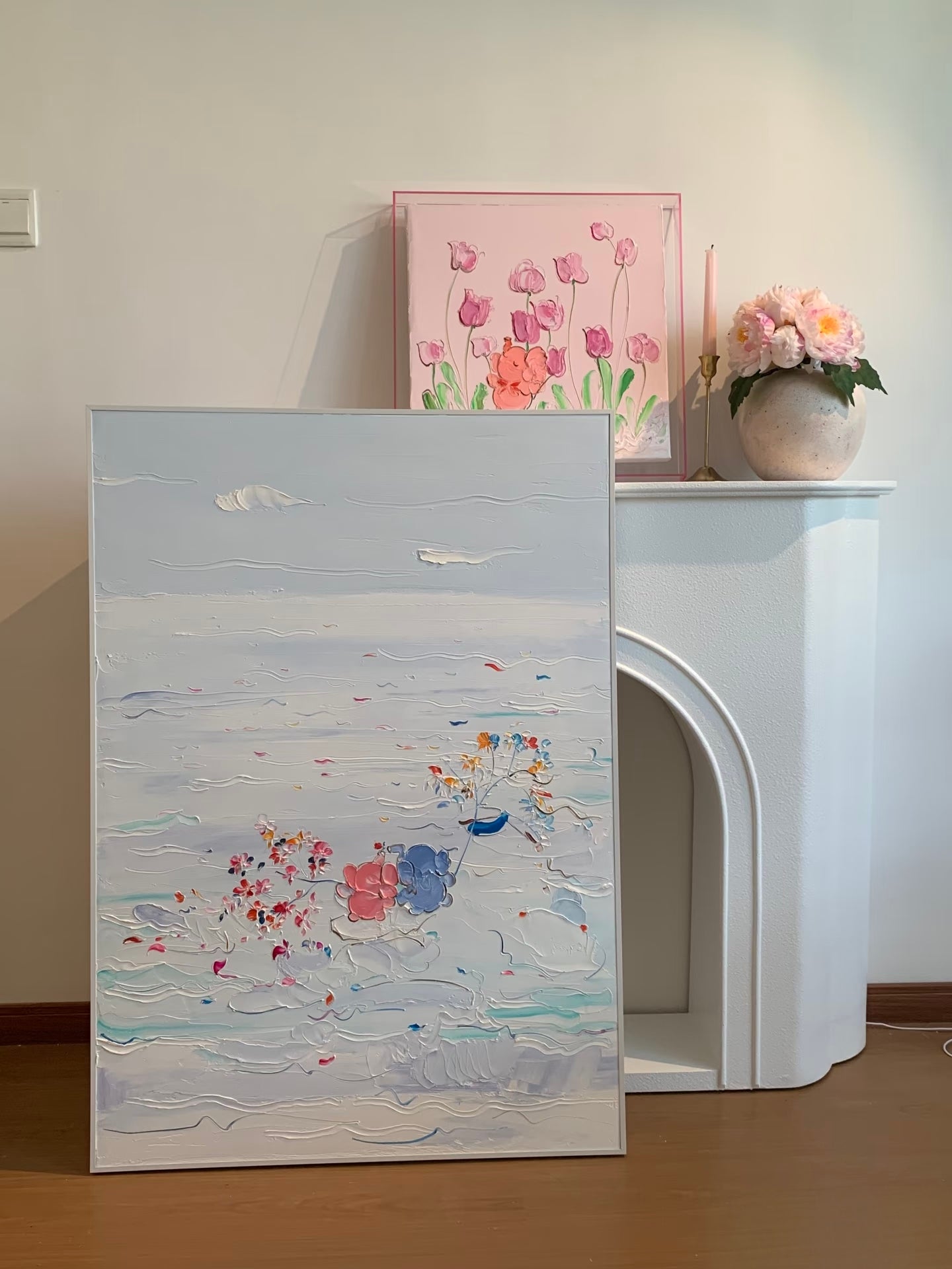 Blue and white floral ocean painting shown beside a modern fireplace