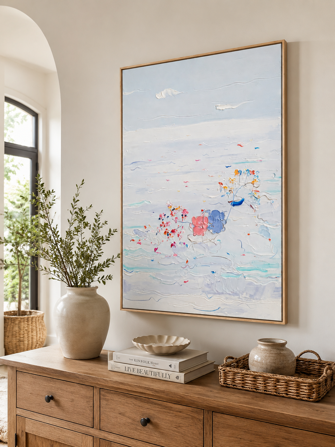 Vertical coastal wall art above a wood console in a bright entryway