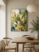 Large abstract botanical wall art with green foliage and warm orange accents displayed in an open dining room