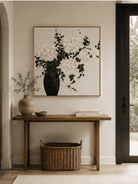 White hydrangea vase painting displayed above a wood console in a modern neutral entryway