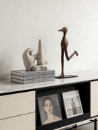 abstract biomorphic resin sculptures, sandstone texture stone art and wood finish running bird figurine on a bookshelf.