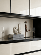 abstract biomorphic resin sculptures, sandstone texture stone art and wood finish running bird figurine on a bookshelf.