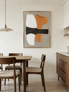 Hand-painted modern organic abstract painting featuring a vibrant orange shape and thick charcoal brushstroke on a sand background in a gold frame.