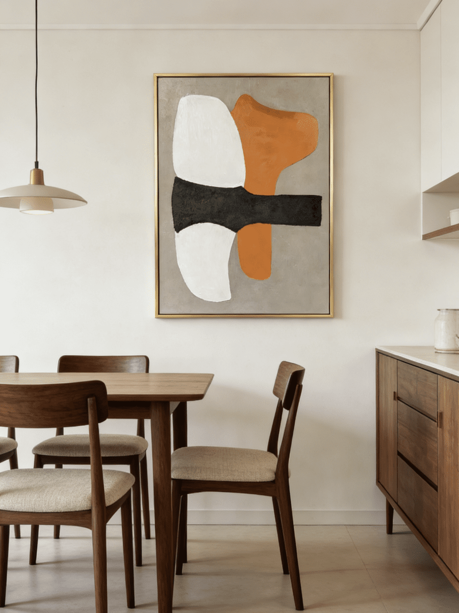 Hand-painted modern organic abstract painting featuring a vibrant orange shape and thick charcoal brushstroke on a sand background in a gold frame.