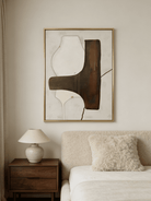 Hand-painted organic modern abstract painting featuring stone-textured background, brown and black shapes in a gold floater frame.