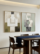 A pair of large vertical abstract paintings with geometric totem-like shapes in sage green, olive, and beige with visible heavy texture.