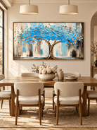 Hand-painted blue tree canvas painting displayed in a modern open dining room with neutral decor.