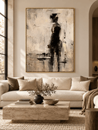 Minimalist abstract woman in black painting displayed in a modern living room with warm neutral decor.