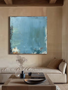 Large blue distressed textured abstract oil painting hand-painted on canvas by Akari Kobayashi, with a floating gold frame on a white background. Perfect for a living room wall.